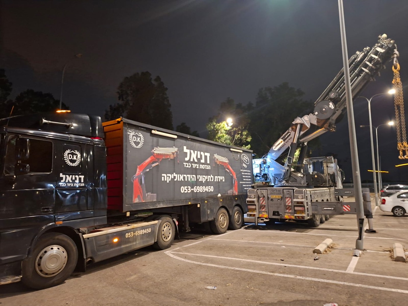 משאית ניידת השירות הממותגת של דניאל לצד מנוף בשעת לילה
